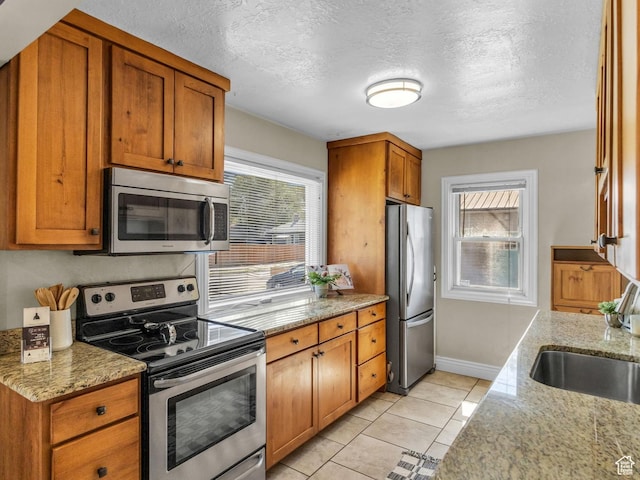 6 W Miller St S, Salt Lake City, UT 84107 - kitchen with appliances with stainless steel finishes, a textured ceiling, brown cabinetry, and light tile patterned floors