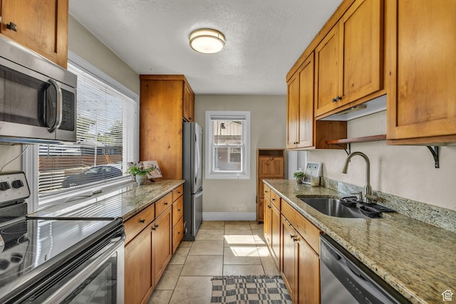 6 W Miller St S, Salt Lake City, UT 84107 - kitchen with appliances with stainless steel finishes, brown cabinets, light stone counters, a textured ceiling, and light tile patterned floors