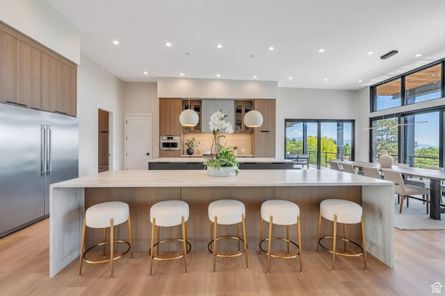 3943 N Foothill Dr, Provo, UT 84604 - kitchen featuring appliances with stainless steel finishes, a large island with sink, modern cabinets, light countertops, and light wood-style floors