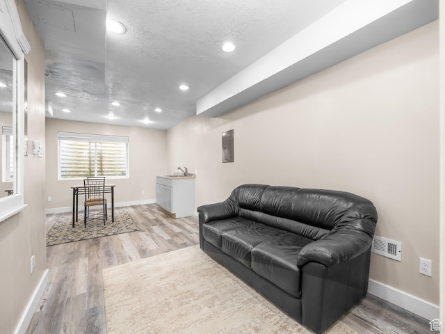 4113 E Cattle Dr, Eagle Mountain, UT 84005 - living room featuring light wood finished floors, recessed lighting, baseboards, a textured ceiling, and electric panel