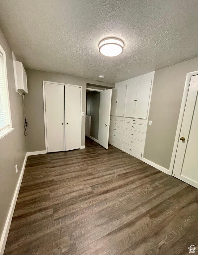 947 W 1300 N, Carbonville, UT 84501 - unfurnished bedroom with dark wood-type flooring, a textured ceiling, baseboards, and two closets