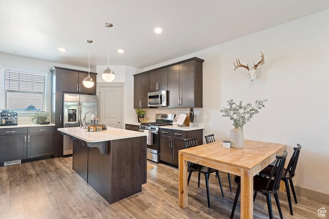 1940 S 200 W Unit 11, Bountiful, UT 84010 - kitchen featuring appliances with stainless steel finishes, light countertops, a center island with sink, dark brown cabinetry, and light wood-style floors