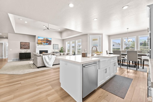 9447 N Arrowhead Dr, Eagle Mountain, UT 84005 - kitchen with stainless steel dishwasher, a sink, a ceiling fan, a lit fireplace, and light wood-style flooring