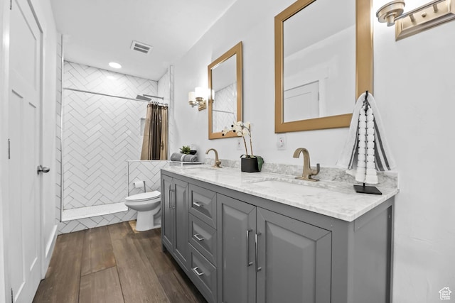 9447 N Arrowhead Dr, Eagle Mountain, UT 84005 - bathroom featuring toilet, double vanity, tiled shower, hardwood / wood-style flooring, and recessed lighting
