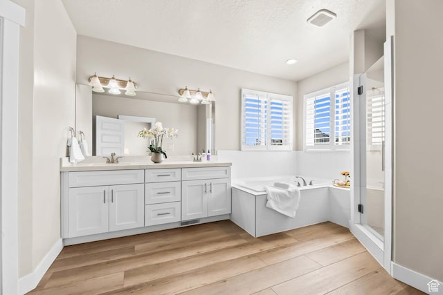 9447 N Arrowhead Dr, Eagle Mountain, UT 84005 - full bathroom with double vanity, a bath, wood finished floors, a stall shower, and a textured ceiling