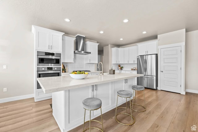 9447 N Arrowhead Dr, Eagle Mountain, UT 84005 - kitchen with stainless steel appliances, wall chimney range hood, baseboards, white cabinets, and light wood-style floors
