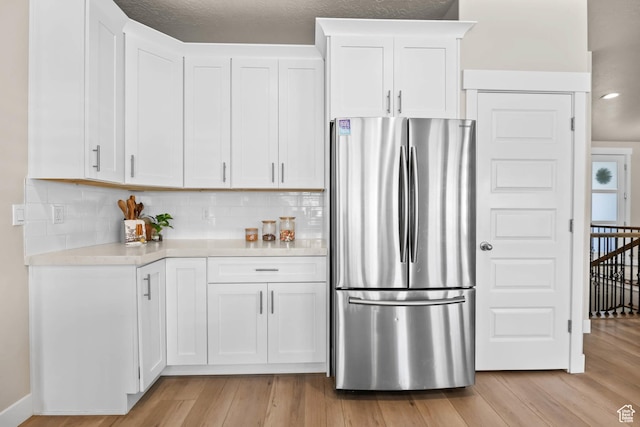 9447 N Arrowhead Dr, Eagle Mountain, UT 84005 - kitchen with freestanding refrigerator, light countertops, light wood-type flooring, white cabinets, and tasteful backsplash