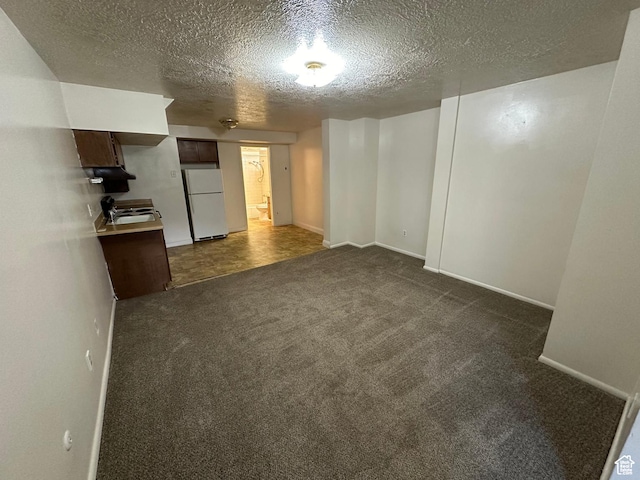 133 W Forest St, Brigham City, UT 84302 - unfurnished living room with dark carpet, baseboards, and a textured ceiling