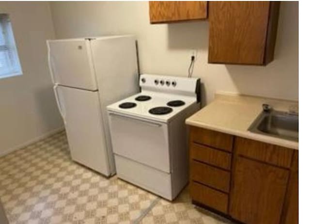 133 W Forest St, Brigham City, UT 84302 - kitchen featuring white appliances, a sink, light flooring, light countertops, and brown cabinets