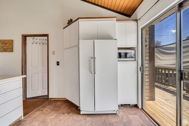 1063 Oxford Dr, Ogden, UT 84403 - kitchen with white refrigerator, stainless steel microwave, white cabinetry, lofted ceiling, and wood ceiling