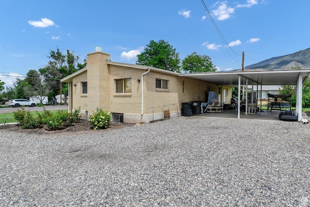 162 E 200 N, Monroe, UT 84754 - back of house with a chimney, an attached carport, brick siding, gravel driveway, and a mountain view