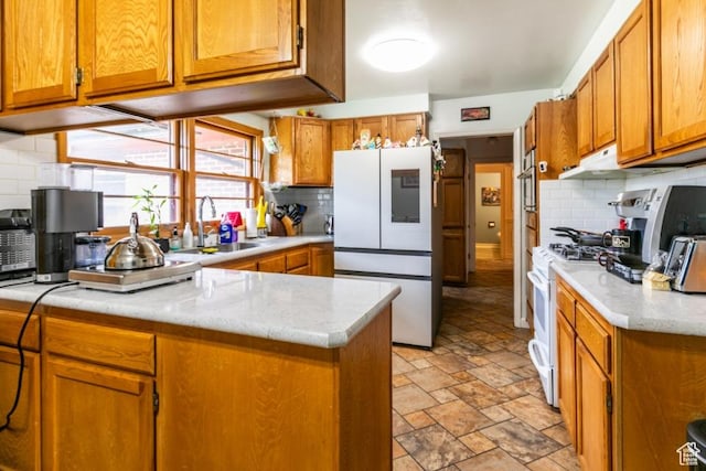 611 E 100 N, Brigham City, UT 84302 - kitchen featuring white appliances, brown cabinets, backsplash, light stone finish floors, and a peninsula