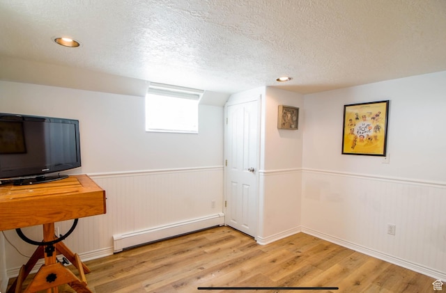 331 W Elberta Dr, Pleasant View, UT 84414 - below grade area featuring a baseboard radiator, a textured ceiling, light wood-type flooring, wainscoting, and baseboards