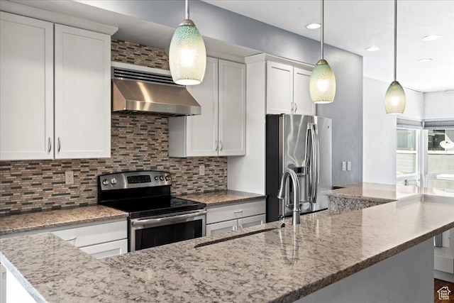 4746 W S Jordan Pkwy, South Jordan, UT 84009 - kitchen with appliances with stainless steel finishes, wall chimney exhaust hood, decorative backsplash, white cabinetry, and pendant lighting