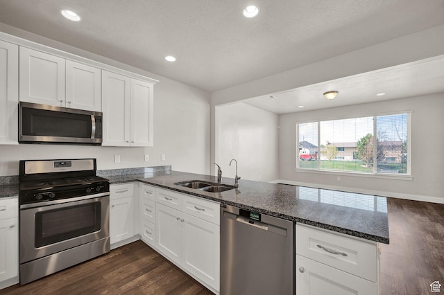 1712 W Naxos Ln, South Jordan, UT 84095 - kitchen with appliances with stainless steel finishes, a sink, a peninsula, dark wood-style floors, and dark stone counters