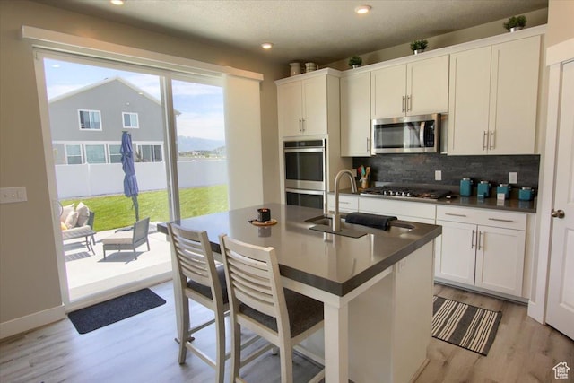 2895 S 2900 W, Syracuse, UT 84075 - kitchen with stainless steel appliances, a sink, dark countertops, decorative backsplash, and light wood finished floors