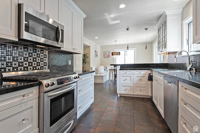 2300 Comstock Dr, Park City, UT 84060 - kitchen with stainless steel appliances, dark countertops, a peninsula, decorative backsplash, and recessed lighting