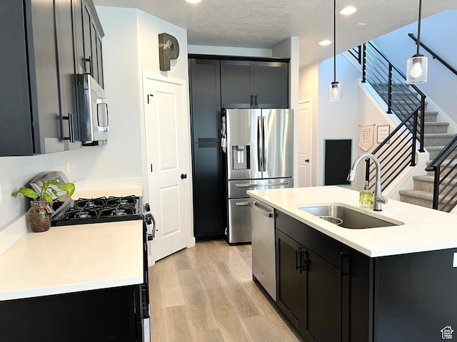 3333 W 3745th St S, West Haven, UT 84401 - kitchen with stainless steel appliances, light wood-style floors, dark cabinetry, light countertops, and pendant lighting