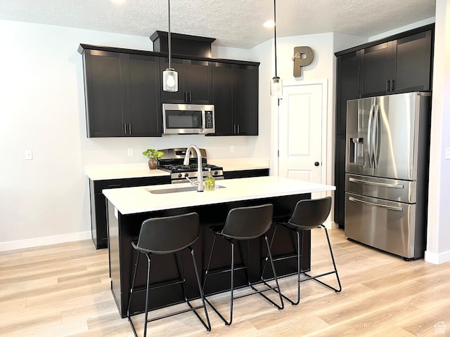 3333 W 3745th St S, West Haven, UT 84401 - kitchen with appliances with stainless steel finishes, dark cabinetry, a textured ceiling, and hanging light fixtures