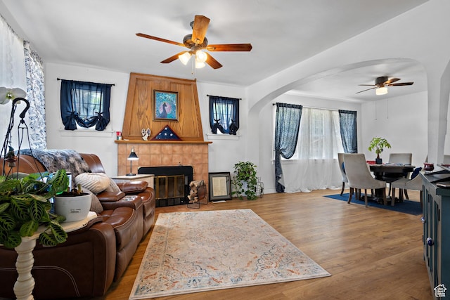 160 S 200 W, Tooele, UT 84074 - living area featuring a ceiling fan, arched walkways, a tiled fireplace, wood finished floors, and baseboards