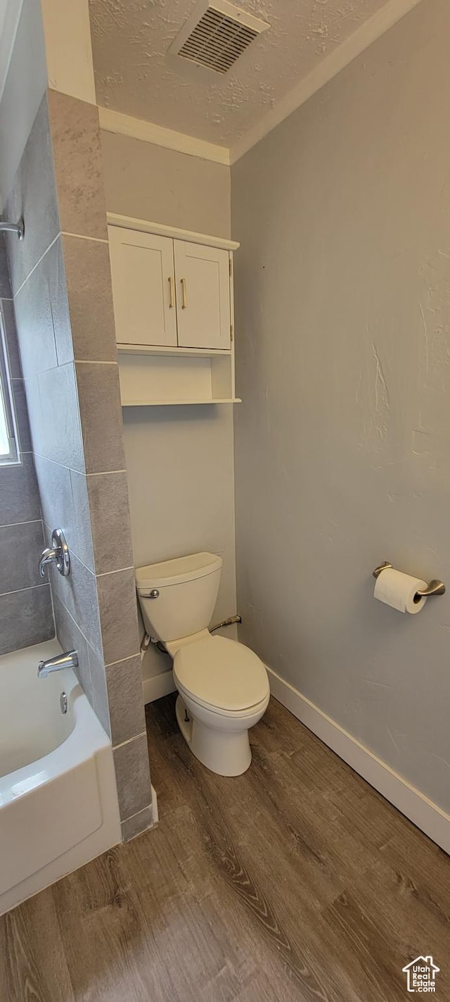 325 W Apple St, Grantsville, UT 84029 - bathroom with wood finished floors, toilet, bathtub / shower combination, and a textured ceiling