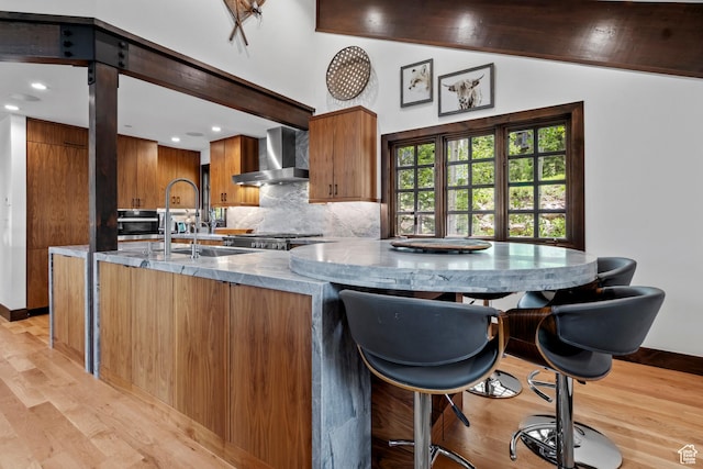 8120 Cache Dr Unit 9, Park City, UT 84060 - kitchen with wall chimney exhaust hood, light wood-type flooring, brown cabinetry, a sink, and backsplash