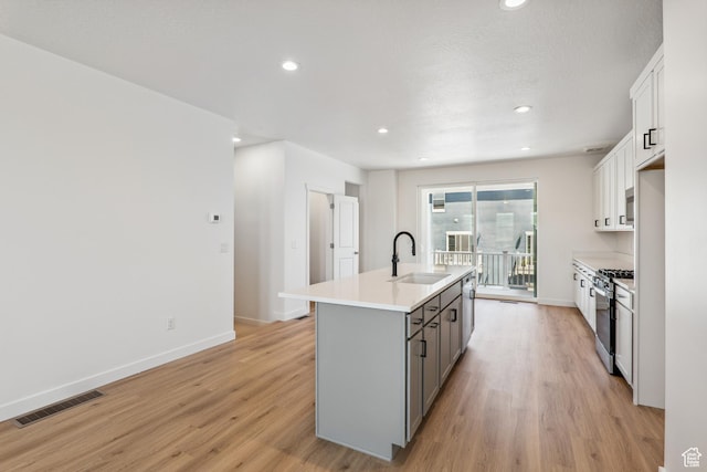 6656 W 11800 S Unit 619, South Jordan, UT 84009 - kitchen with a sink, gray cabinetry, stainless steel range with gas stovetop, a kitchen island with sink, and light wood finished floors