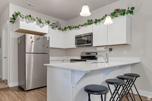 3722 W 1440 N Unit F301, Lehi, UT 84043 - kitchen featuring appliances with stainless steel finishes, a peninsula, baseboards, a kitchen breakfast bar, and light wood finished floors