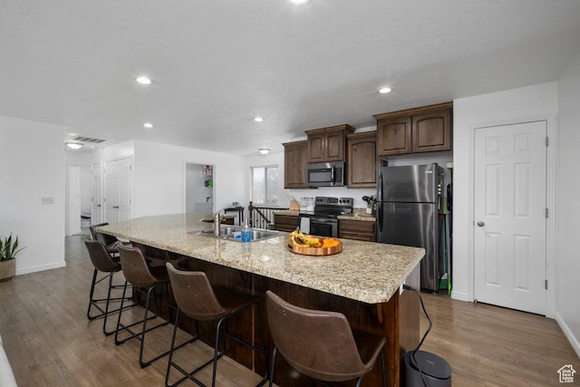 29 E 150 N, American Fork, UT 84003 - kitchen featuring stainless steel appliances, a sink, a kitchen island with sink, dark wood-type flooring, and a breakfast bar