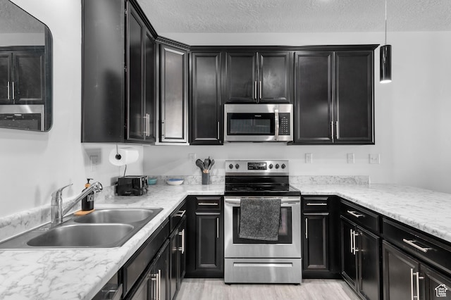 347 N 750 E, Vineyard, UT 84059 - kitchen with appliances with stainless steel finishes, dark cabinets, a sink, a textured ceiling, and light wood finished floors