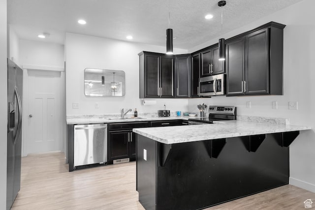 347 N 750 E, Vineyard, UT 84059 - kitchen featuring stainless steel appliances, a sink, dark cabinetry, a peninsula, and light wood-style flooring