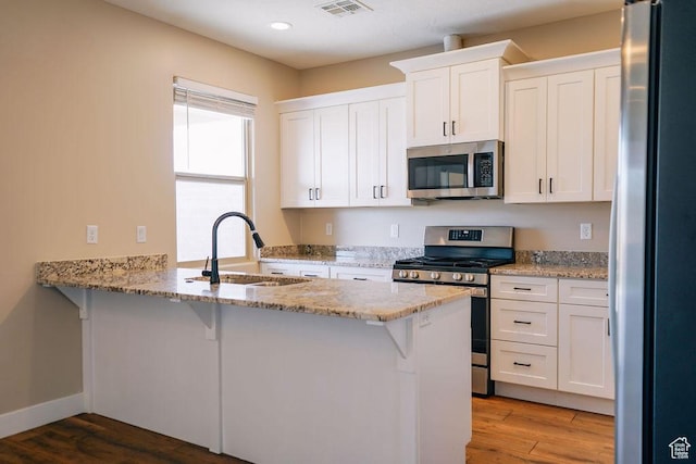 579 N Staci Dr, Hurricane, UT 84737 - kitchen featuring stainless steel appliances, a peninsula, white cabinetry, recessed lighting, and wood finished floors