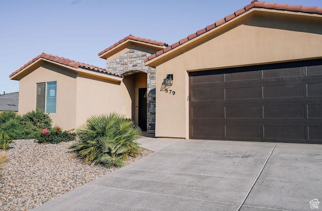 579 N Staci Dr, Hurricane, UT 84737 - mediterranean / spanish-style house with a tile roof, stone siding, driveway, stucco siding, and a garage