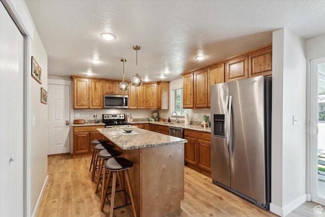 846 E 5600 S, South Ogden, UT 84405 - kitchen with stainless steel appliances, a center island, light wood-style floors, a textured ceiling, and a kitchen bar
