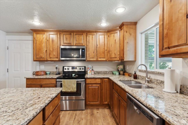 846 E 5600 S, South Ogden, UT 84405 - kitchen with stainless steel appliances, a textured ceiling, light wood-style floors, light stone countertops, and brown cabinetry