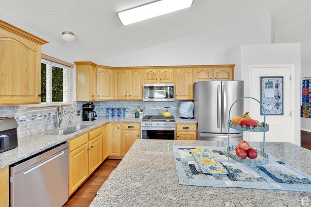 7443 W Perennial Dr, Magna, UT 84044 - kitchen with stainless steel appliances, vaulted ceiling, light brown cabinets, decorative backsplash, and wood finished floors