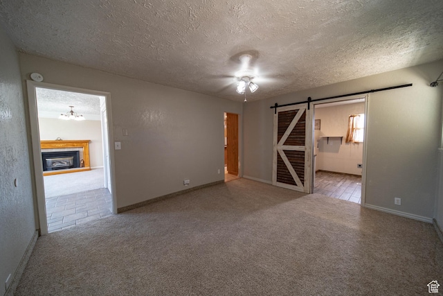 617 Aspen Cir, Price, UT 84501 - spare room featuring a barn door, carpet flooring, a textured ceiling, a glass covered fireplace, and a chandelier
