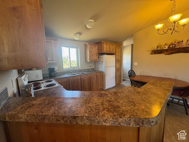 6430 S 37280 W Unit 40, Fruitland, UT 84027 - kitchen with white appliances, brown cabinetry, a chandelier, and a peninsula