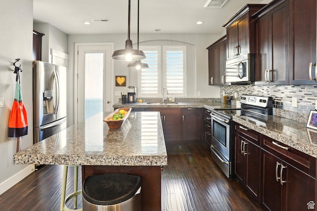 4746 W Daybreak Rim Way S, Jordan, UT 84009 - kitchen with appliances with stainless steel finishes, dark wood finished floors, a kitchen bar, backsplash, and a kitchen island
