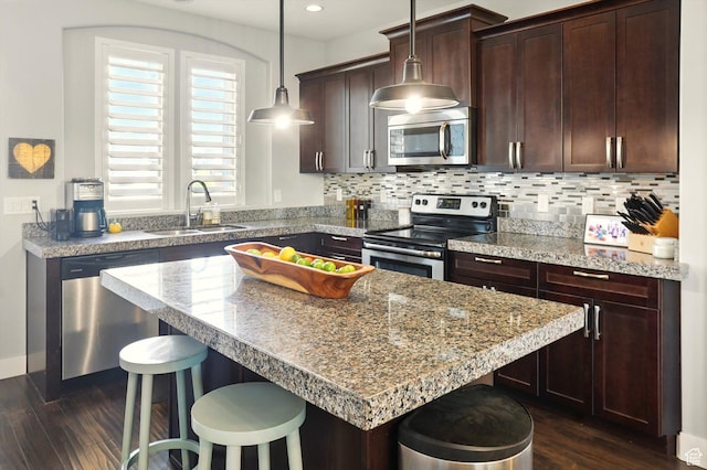 4746 W Daybreak Rim Way S, Jordan, UT 84009 - kitchen featuring appliances with stainless steel finishes, a breakfast bar area, dark wood-type flooring, dark brown cabinets, and backsplash