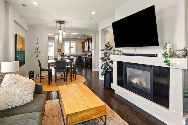 4746 W Daybreak Rim Way S, Jordan, UT 84009 - living area featuring a glass covered fireplace, dark wood finished floors, recessed lighting, and arched walkways