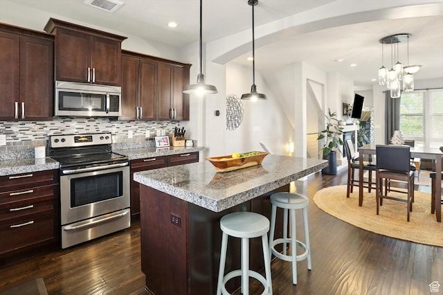 4746 W Daybreak Rim Way S, Jordan, UT 84009 - kitchen with appliances with stainless steel finishes, dark wood-style flooring, decorative backsplash, a center island, and a breakfast bar