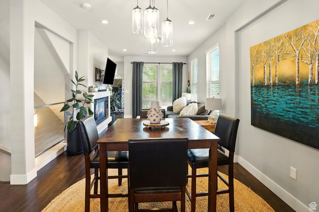 4746 W Daybreak Rim Way S, Jordan, UT 84009 - dining space with dark wood-style floors, a glass covered fireplace, recessed lighting, and a chandelier