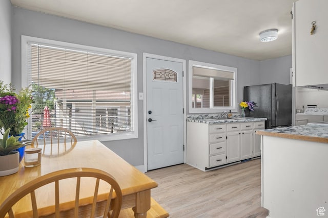 1866 E Village Rd S, Salt Lake City, UT 84121 - kitchen with washing machine and dryer, freestanding refrigerator, white cabinets, light wood-type flooring, and light countertops