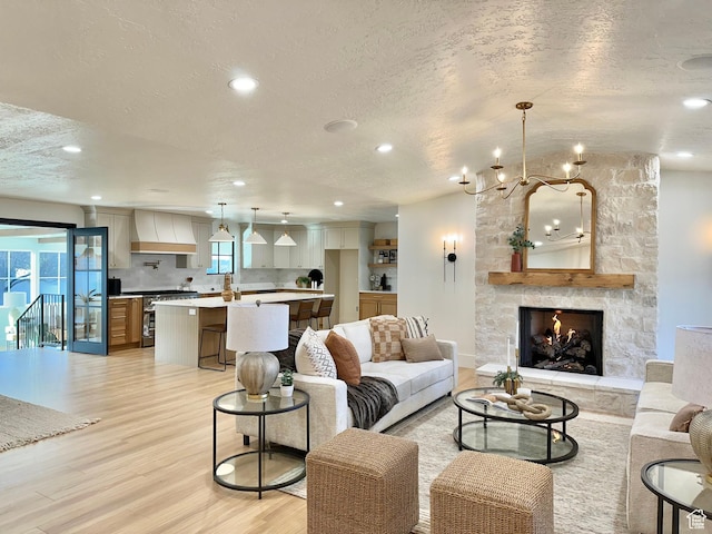 5862 S Ayrshire Dr, Murray, UT 84107 - living room featuring a textured ceiling, light wood-type flooring, a chandelier, recessed lighting, and a fireplace