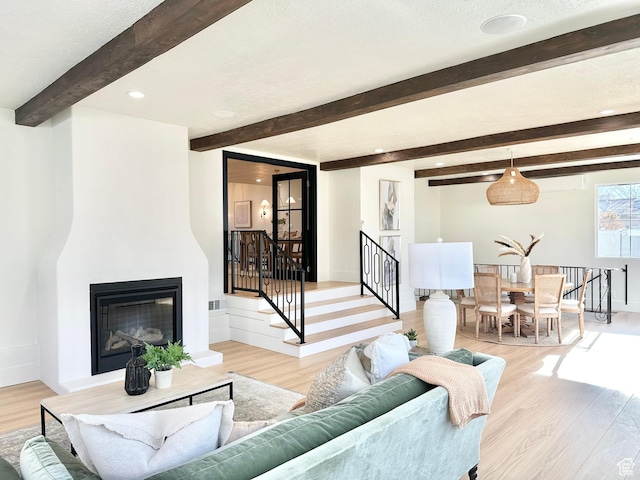 5862 S Ayrshire Dr, Murray, UT 84107 - living area featuring beamed ceiling, light wood-style flooring, a glass covered fireplace, stairs, and recessed lighting