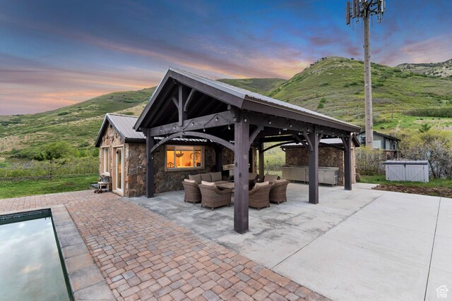 370 S Got Teeth Ln E, Emigration Canyon, UT 84108 - patio terrace at dusk with an outdoor hangout area, a hot tub, a gazebo, a patio area, and a mountain view