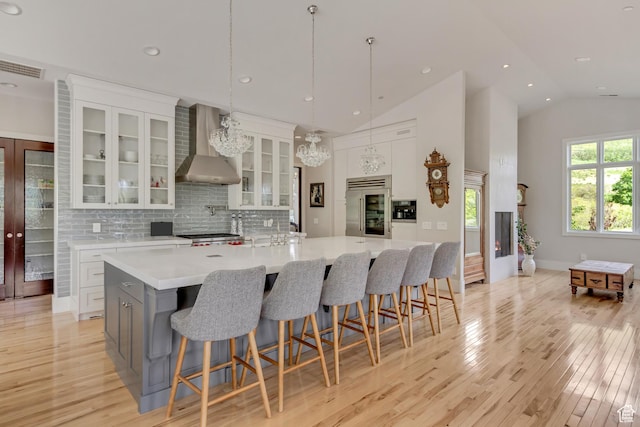 370 S Got Teeth Ln E, Emigration Canyon, UT 84108 - kitchen featuring wall chimney range hood, built in refrigerator, light wood-type flooring, light countertops, and white cabinetry
