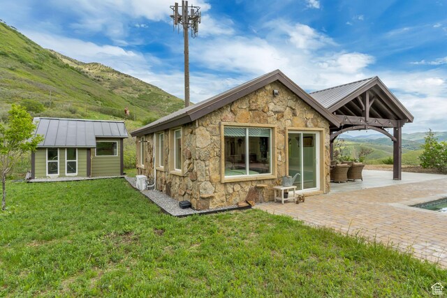 370 S Got Teeth Ln E, Emigration Canyon, UT 84108 - back of house featuring stone siding, a standing seam roof, a patio, a metal roof, and a lawn