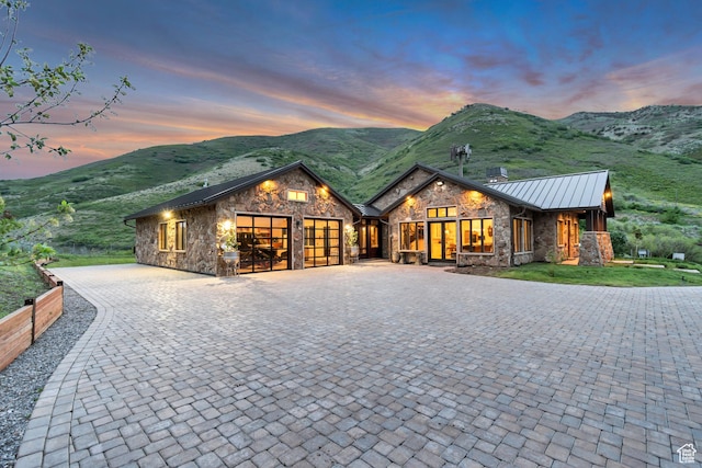 370 S Got Teeth Ln E, Emigration Canyon, UT 84108 - view of front of home with stone siding, decorative driveway, a garage, a standing seam roof, and a mountain view